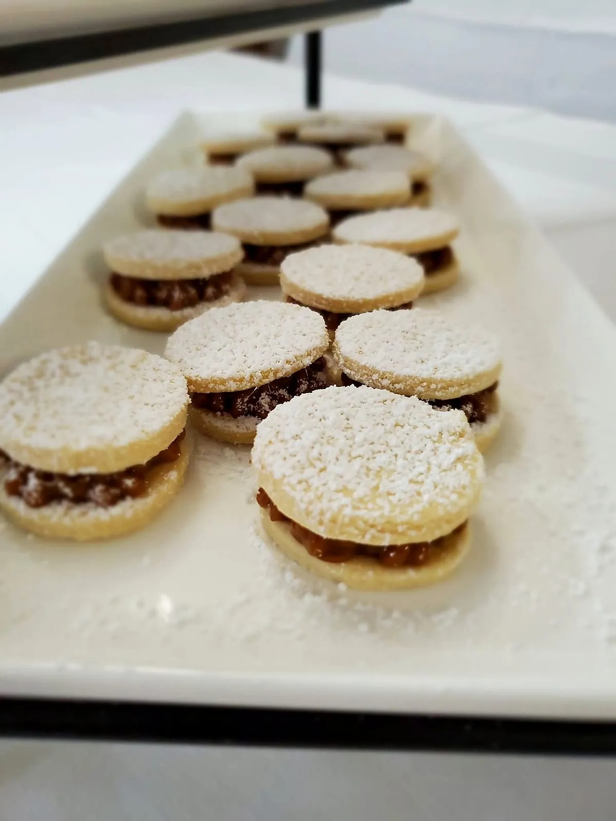 Rows of fresh alfajores on a long white platter
