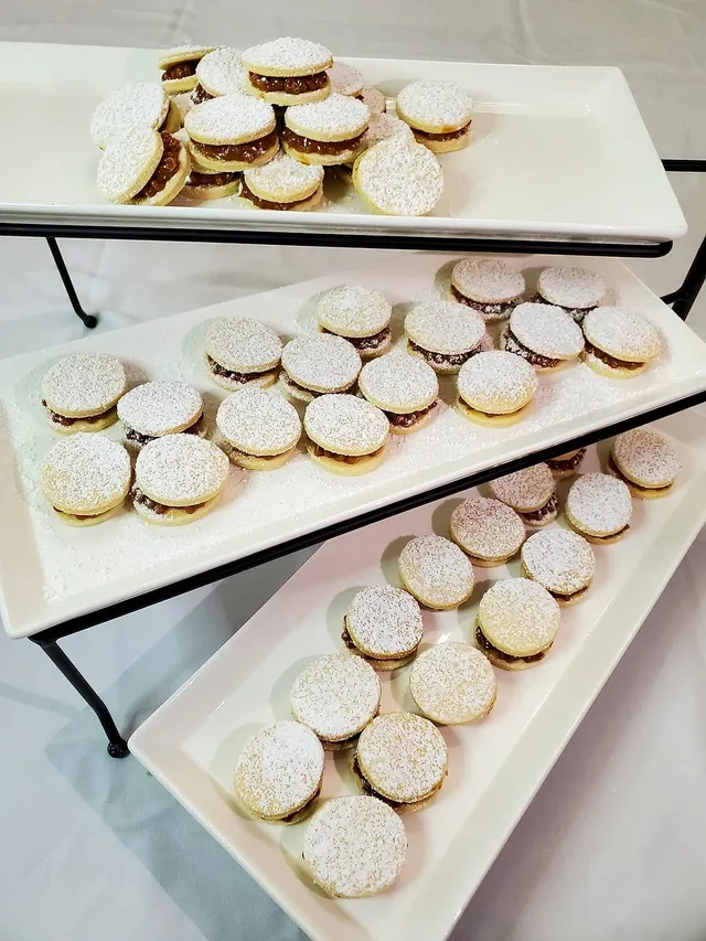 Three-tier stand of powdered alfajores on white platters